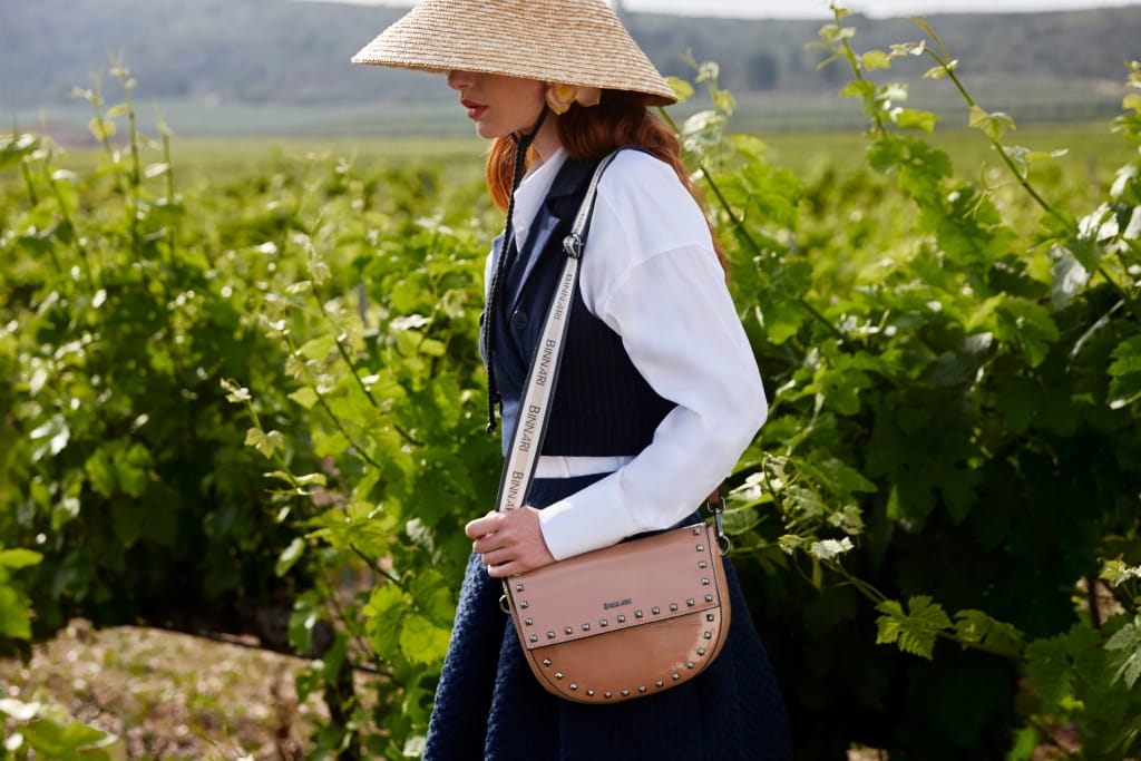 Modelo junto a bolso bandolera Giuliana en viñedo de uvas.