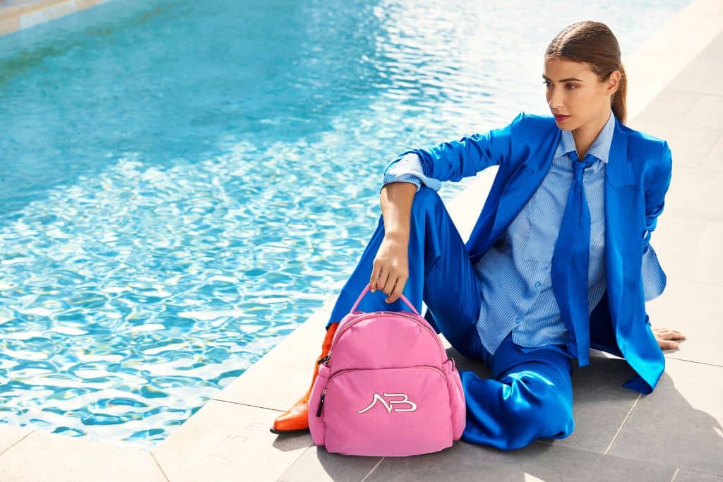 Mujer posa al lado de una piscina con una de las mochilas de Binnari.