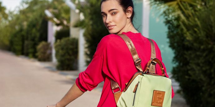 Modelo paseando en bicicleta con la mochila de moda para mujer Mina de la colección primavera-verano Getaway de Binnari.